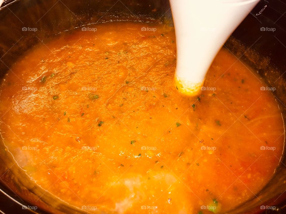 Delicious homemade carrot and coriander soup cooked in a slow cooker. Steaming in the lens. 