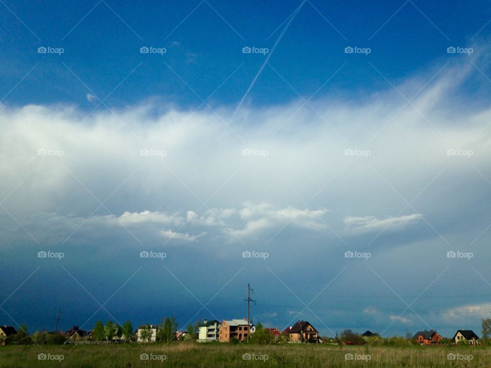 Plane line in the bright sky above the village 