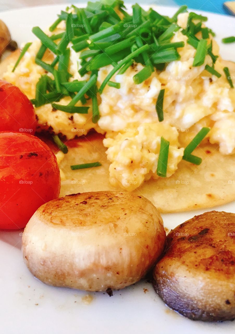 Good morning breakfast of scrambled eggs served atop a crispy corn tortilla, with sides of grilled tomatoes on the vine and mushroom caps and garnished with green chives. This is my version of Chef Gordon Ramsey’s famous scrambled eggs 