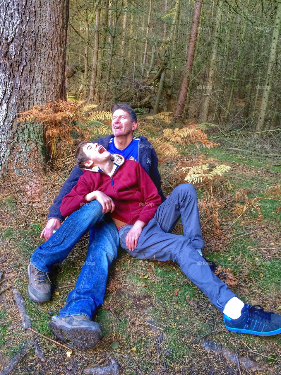 Close-up of happy father and son sitting on grass