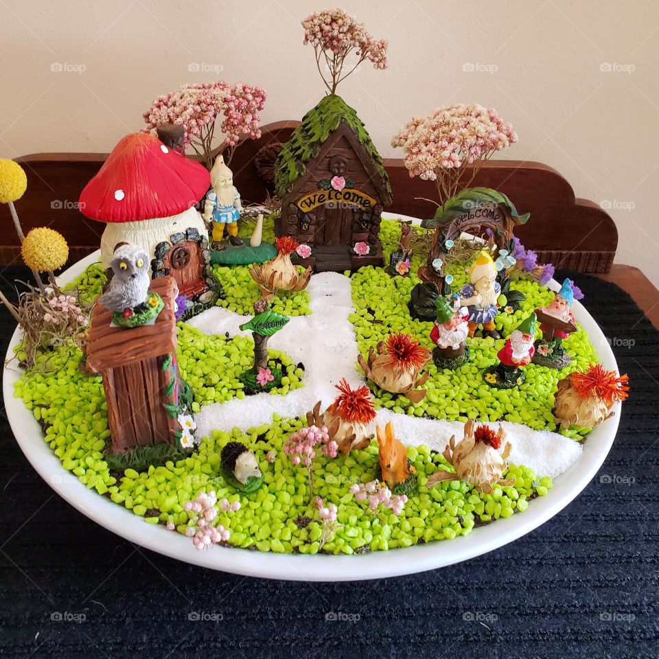 a colorful fairy garden with gnomes, their houses & plants