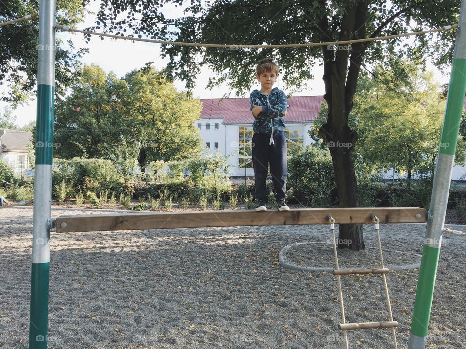 Boy standing proud on bar. Boy standing proud, balancing on wood bar on playground