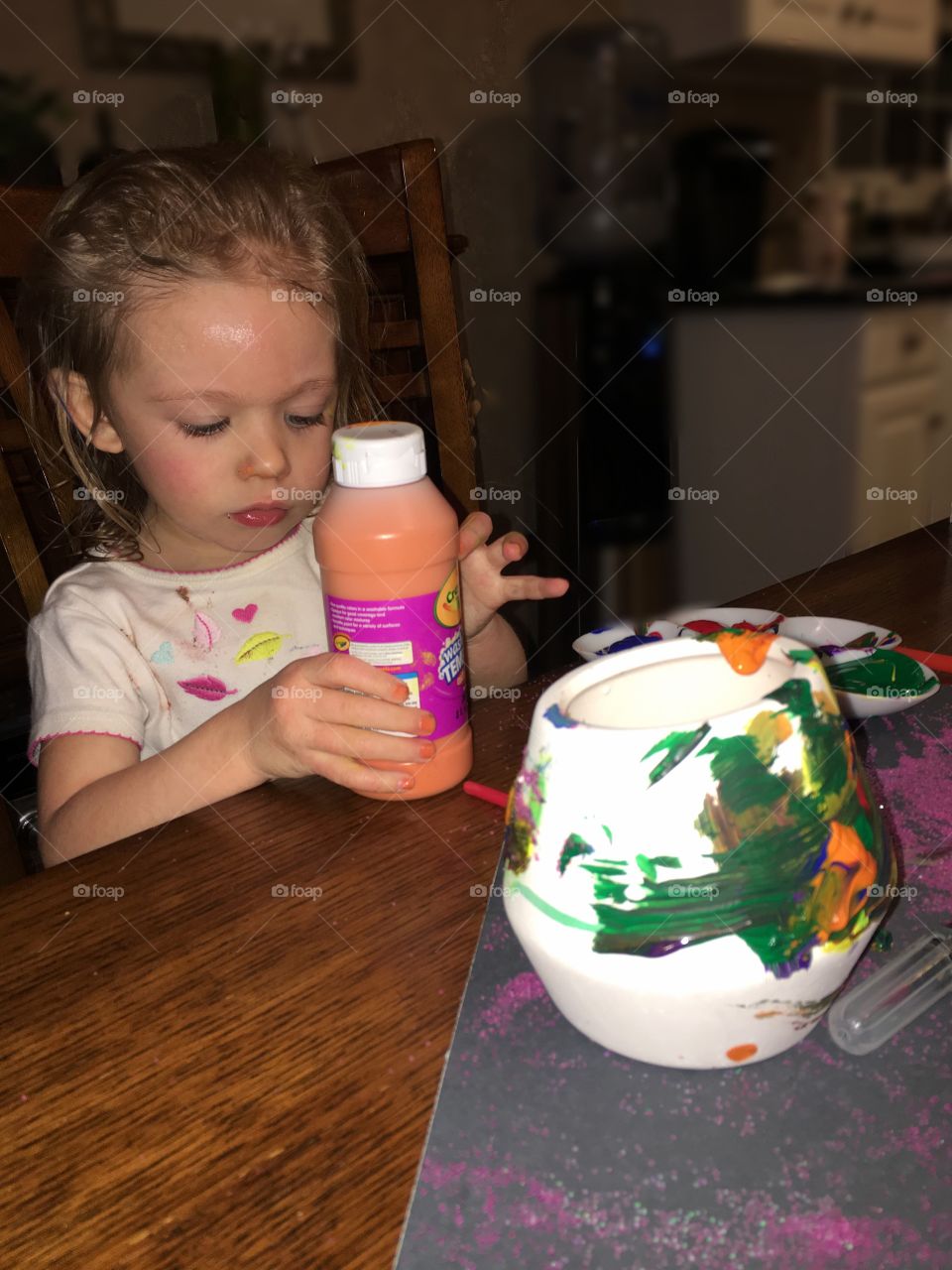 Cute girl holding paint bottle in hand