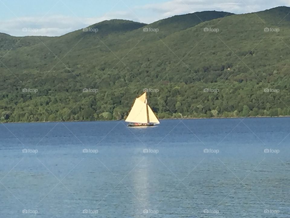 The Hudson River. A lone sail boat drifts through the Hudson River in upstate New York.  