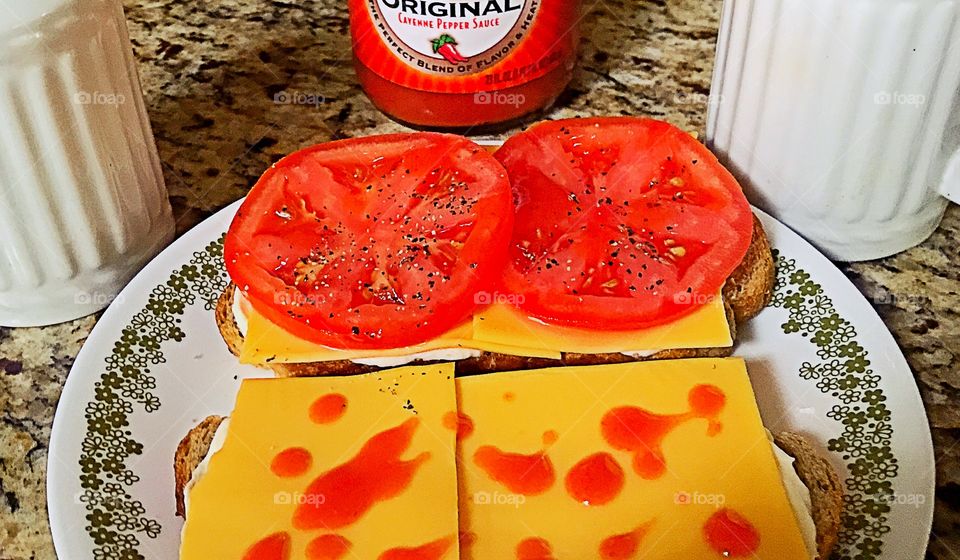 Yellow American and fresh tomatoes on rye toast with mayonnaise!Hot sauce optional.