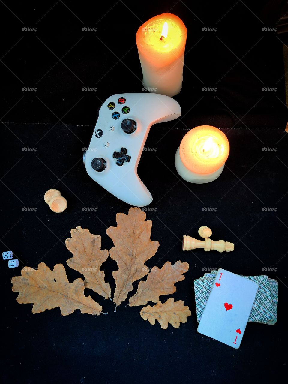 Games in the evening.  Composition.  Autumn oak leaves as pointers to popular games: dice, backgammon, gamepad, chess, cards. There are two burning candles nearby