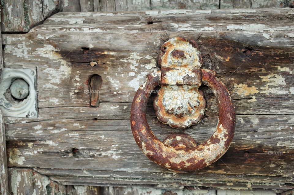 A rusted iron door knocker on an old door