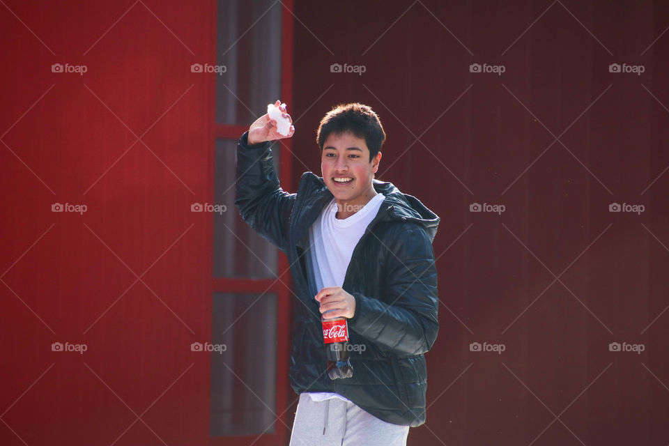 Young handsome man with a bottle of Coca-Cola playing in a snow fight