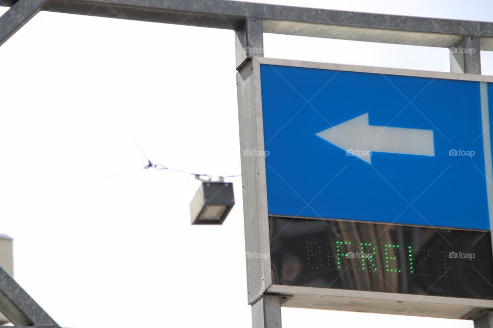 Blue entrance sign with a white arrow into a multi-storey car park and a green open sign