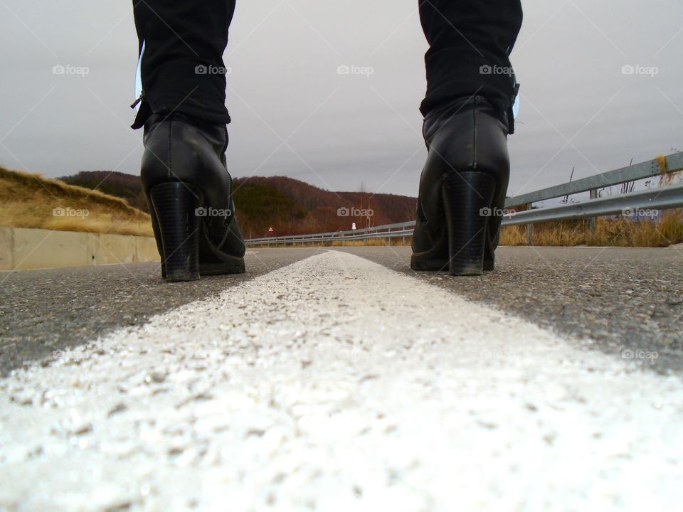 Women's black boots in the middle of the road