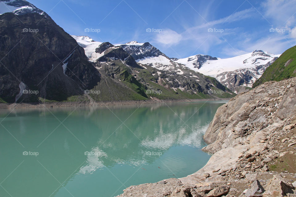 Hiking trail in the mountains, view of  lake and mountain peaks with snow 