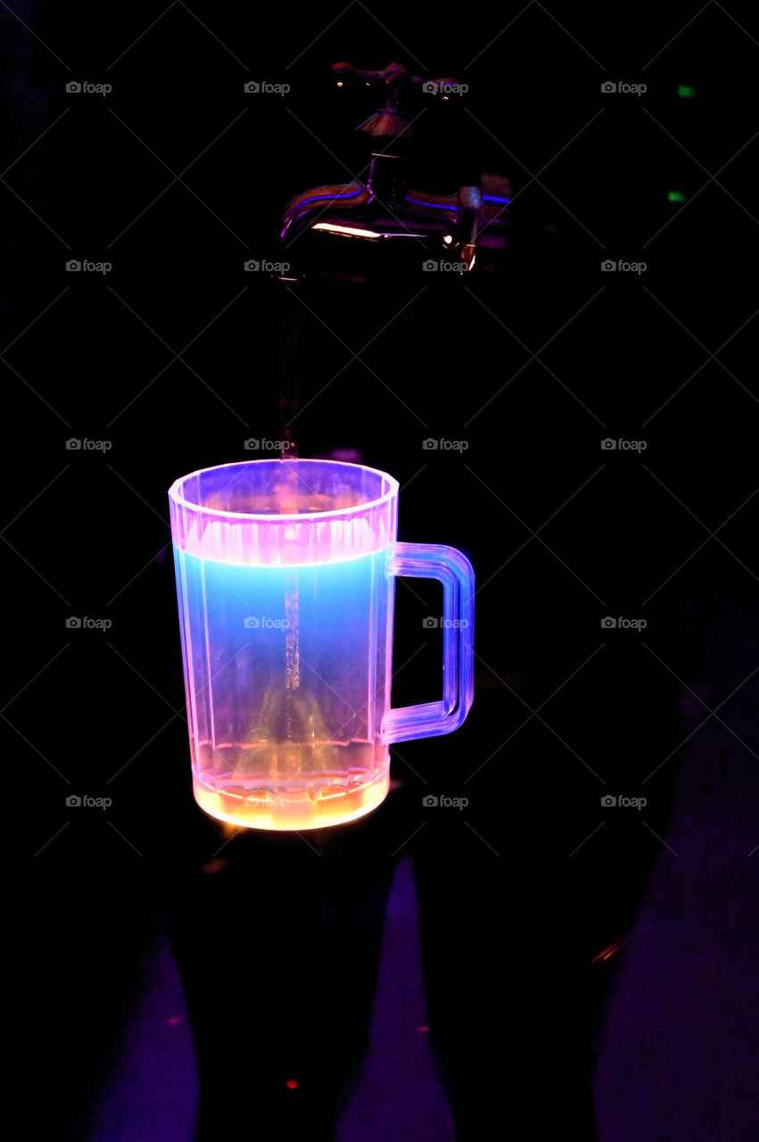 The colorful illuminated drink is floating in the dark.