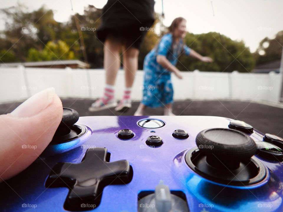 Xbox purple blue colored remote accessory used as if the mother is playing a game called: bring the children on the trampoline and play outside.