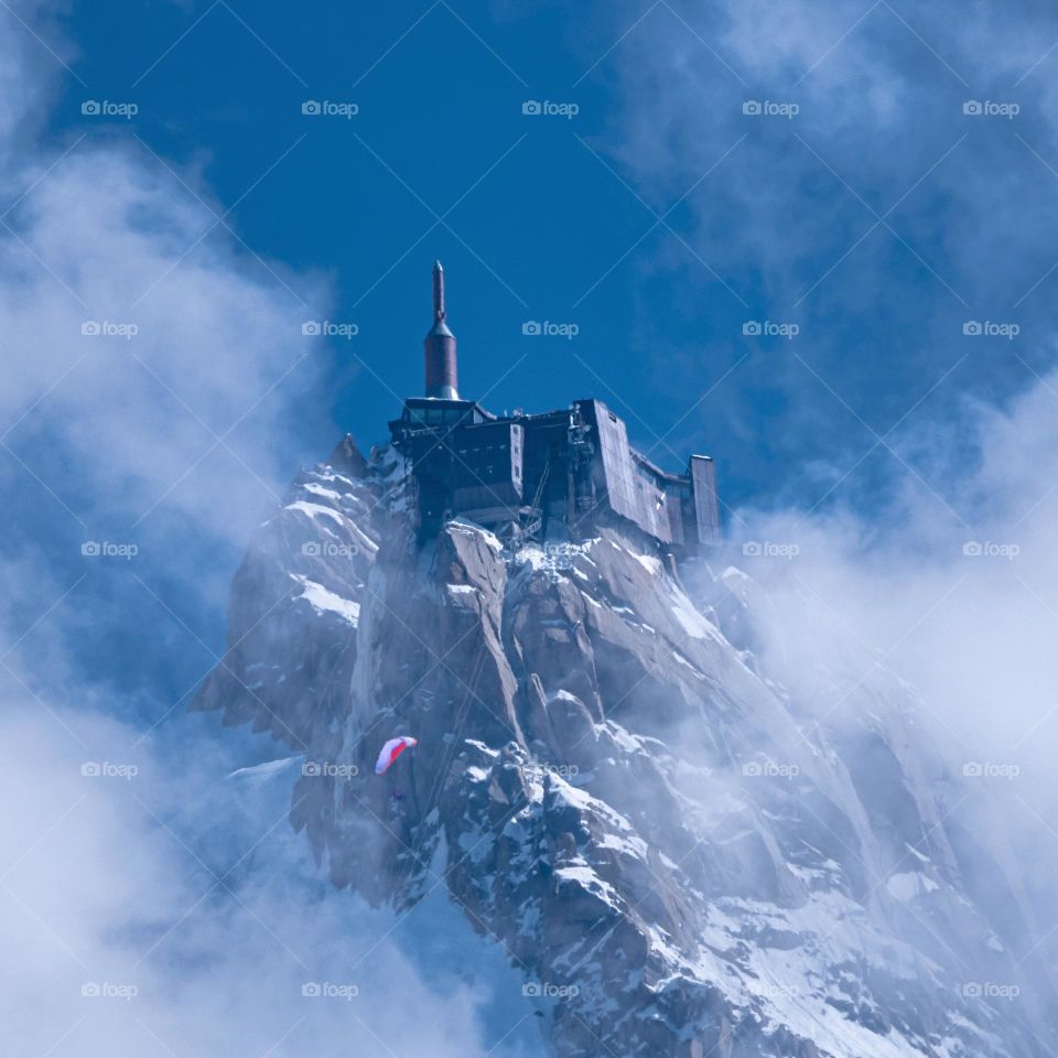 Aiguille du Midi in the clouds with a flying paraglider