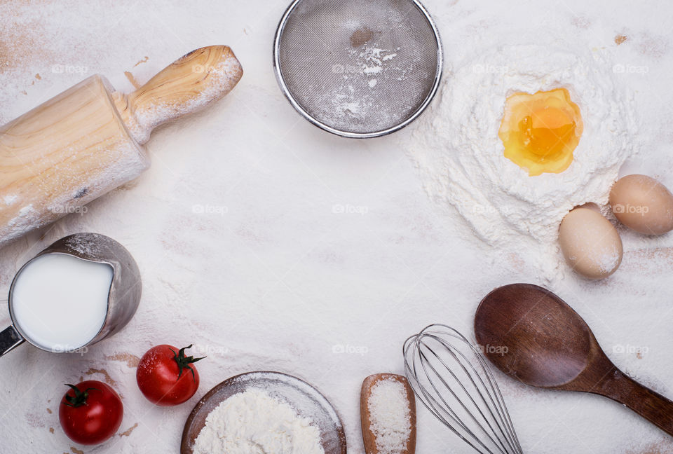 Composition of flour on a table, along with everything you need to cook such as eggs, flour, tomatoes, molder and other