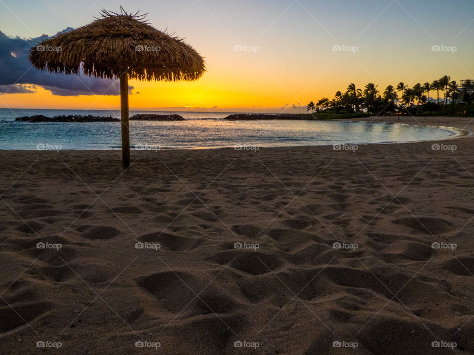 Palapa or thatched umbrella on a tropical beach at sunset.  