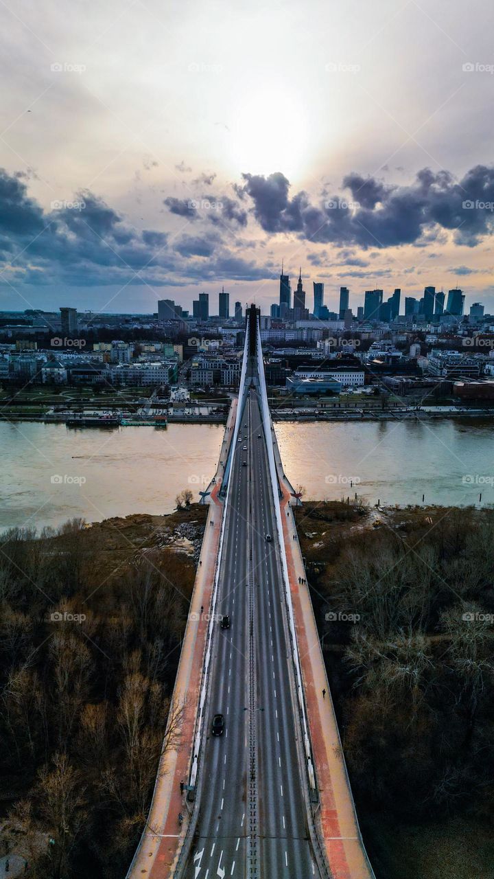 Aerial Świętokrzyski Bridge photo with Wisła river and Warszawa center in background. Cloudy sky with sun 