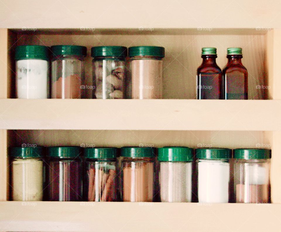 Green Color Story - Spices and flavorings with green lids in a cupboard door spice rack