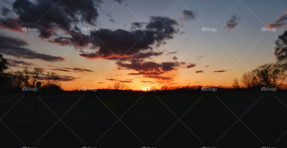 sun sets below hill in country field