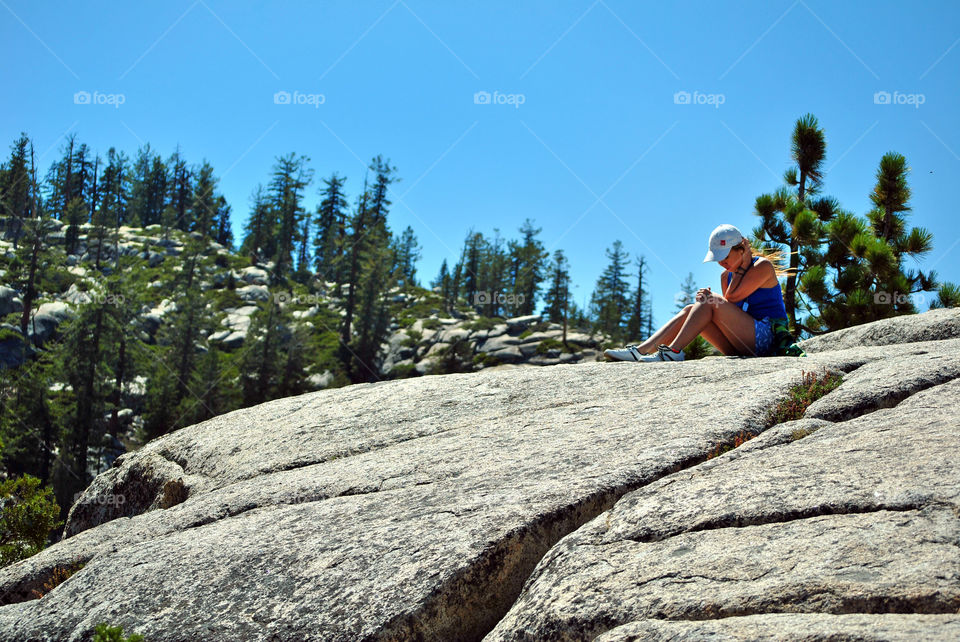 Girl relaxing sitting on top of the mountain rocks after hike