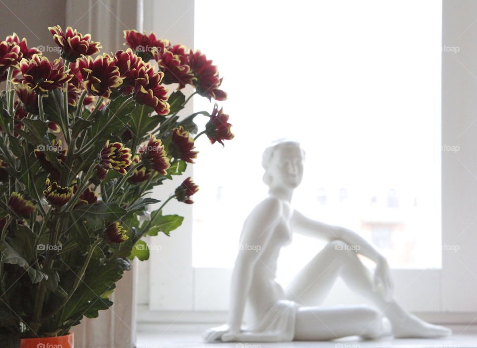 Bouquet of flowers in light window with statue of woman