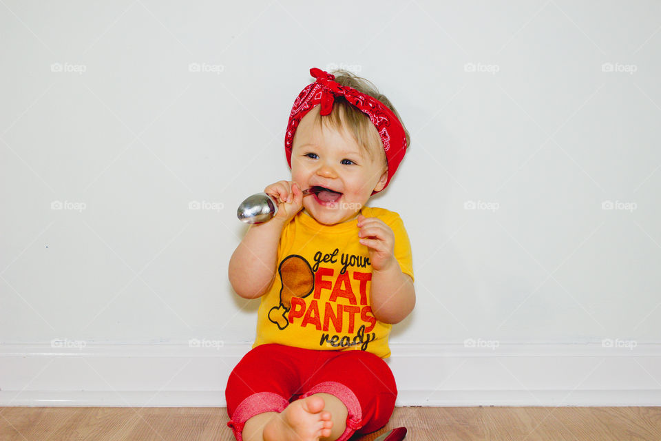 A toddler poses for a Thanksgiving themed photo wearing a shirt that reads, “Get Your Fat Pants Ready”. 