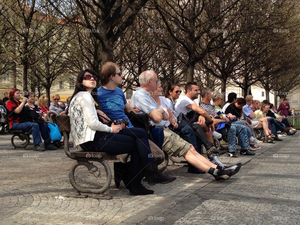 Public sitting in benches relaxing in town square