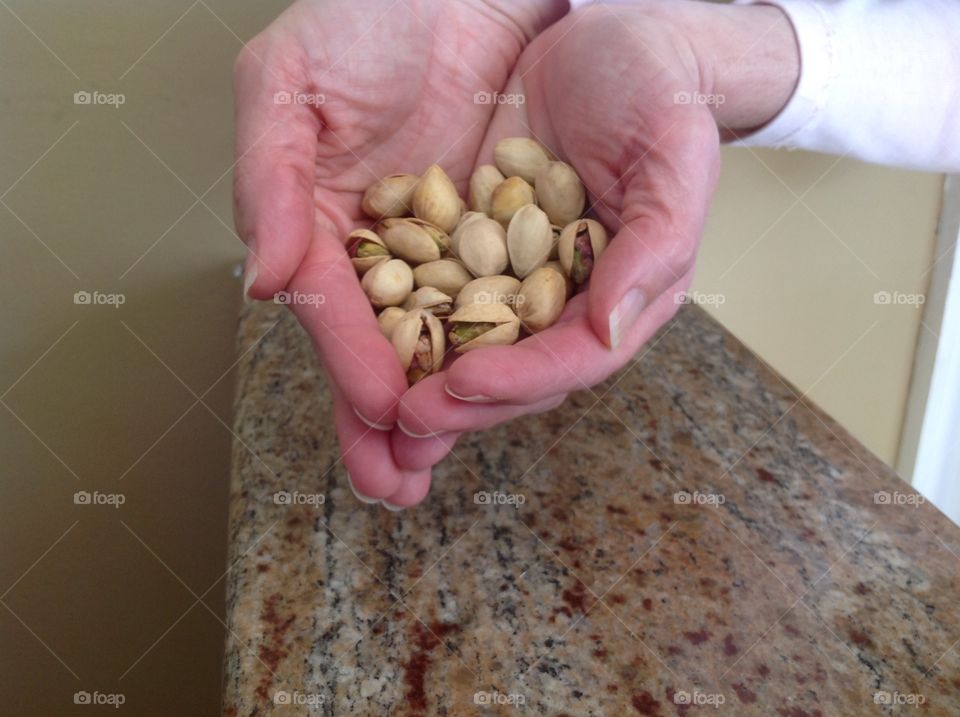 Holding a handful of pistachio nuts.