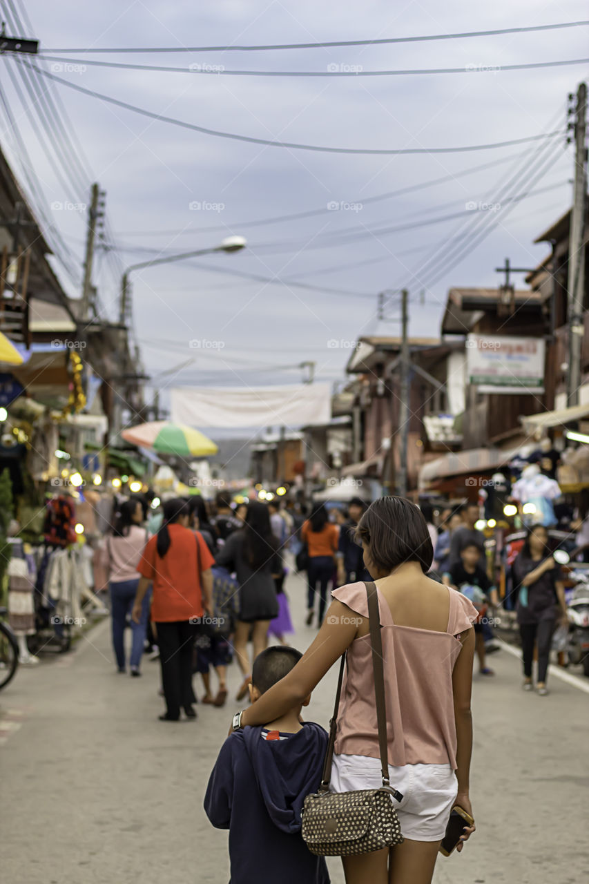 Mother and son on the street and blurry tourists at Walking Street Chiang Khan, Loei in Thailand.