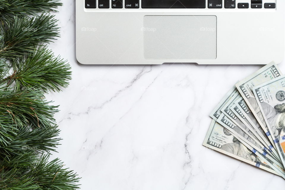 Holiday shopping. Flatlay items. Laptop, cash money one hundred dollars bill, Christmas tree 