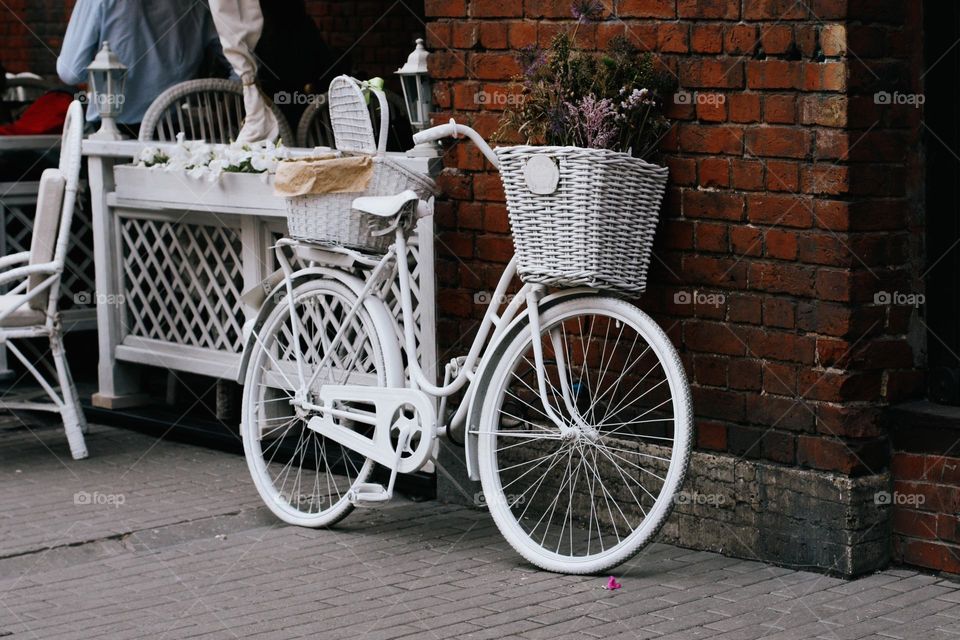 One lonely white bicycle near brick wall 