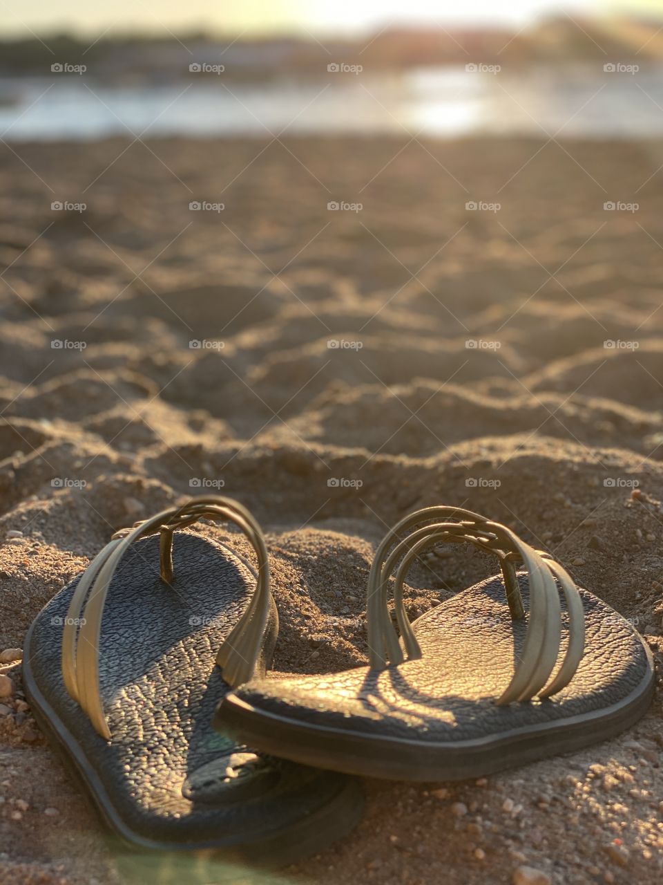 Beautifully naturally lighted photo with women’s sandals in forefront and sun in background. 