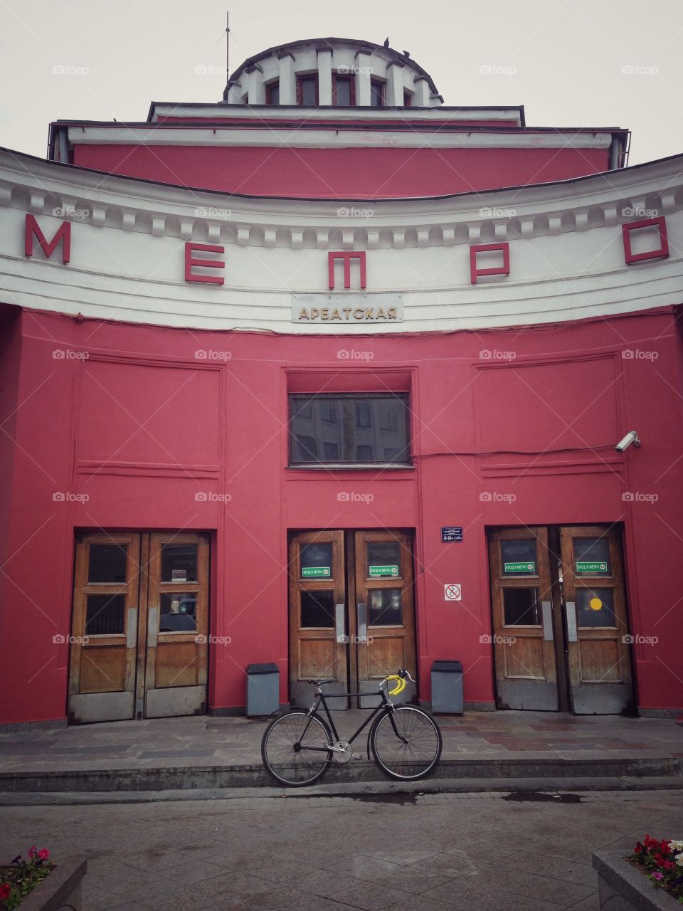 Grey brakeless fixie bike with orange wheels in front of soviet building of underground building in Moscow, Russia