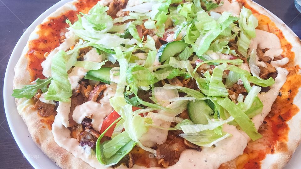 Kebab pizza with kebab, salad, garlic sauce and tomato sauce,