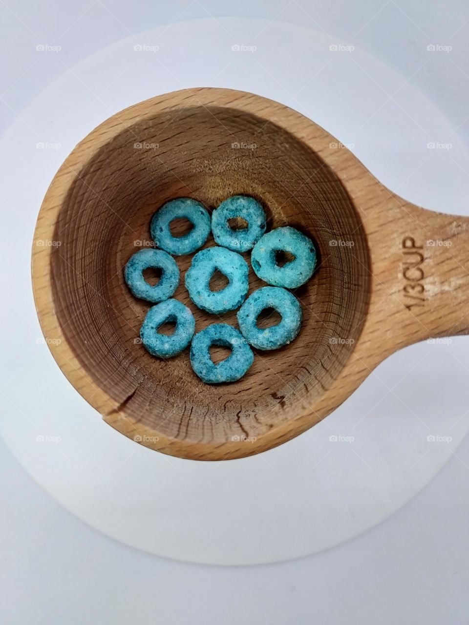 Measuring fruity blue circles in a  wooden measuring cup.