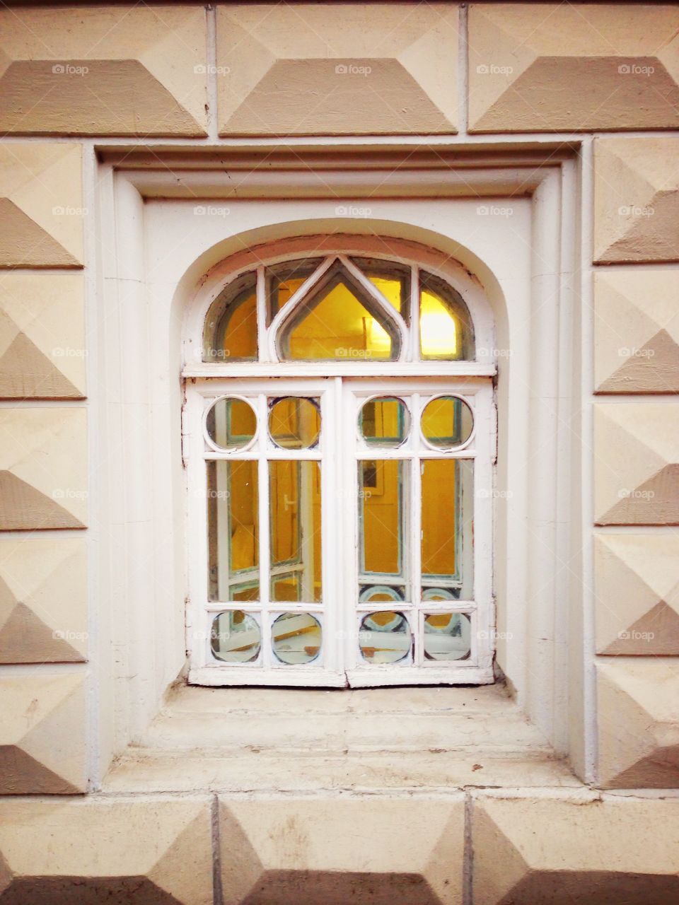 White window of old Russian house with yellow light