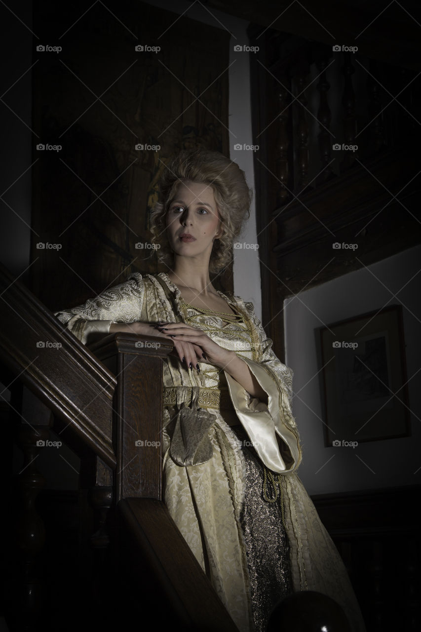 One of a set of photos taken in a 17th century house that is now a restaurant and hotel. The look is based around Marie Antoinette with long luxurious dress and hair styled high. Makeup was very pale and finished using baby powder