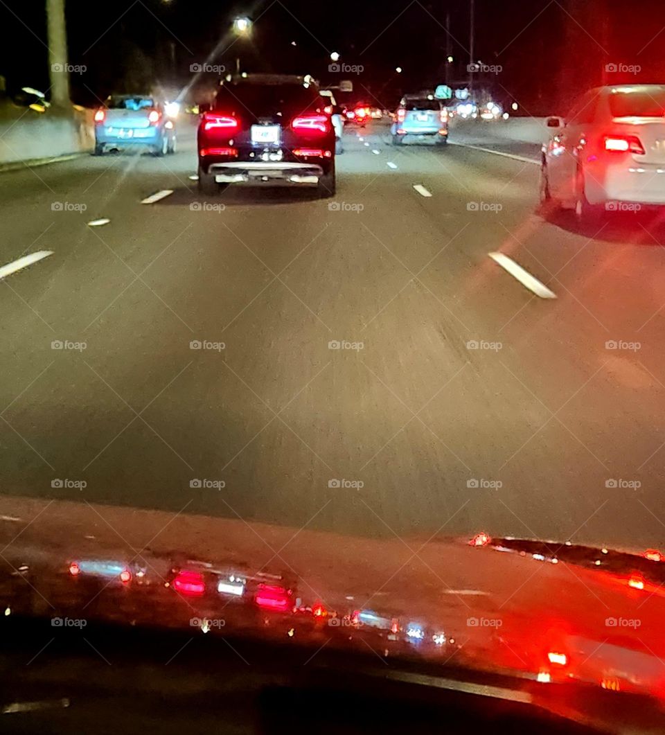 commuter traffic car tail lights reflected in the red hood of the car behind on a week night in Oregon