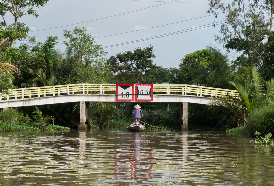 Vietnamese canoe crossing under the bridge.