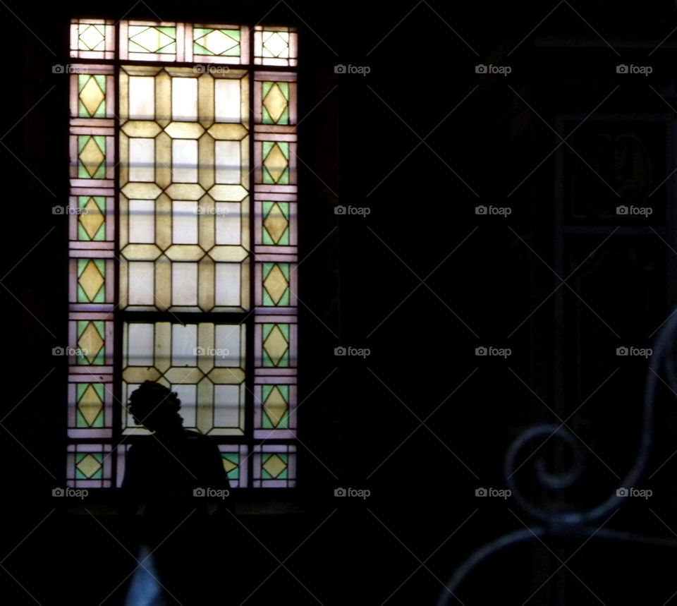 statue silhouette with stained glass in background