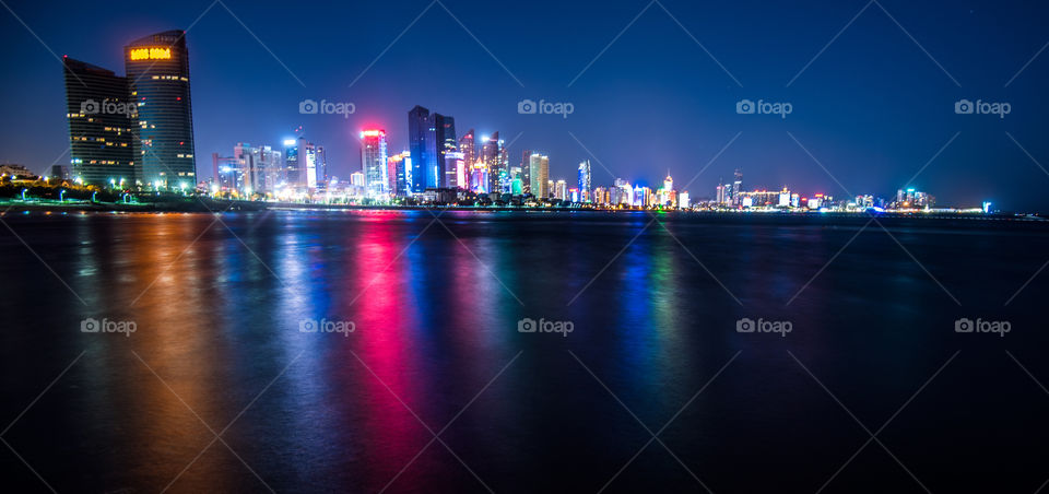 Asia China Qingdao home of Tsingtao Beer, skyline frome seaside at night colorful city