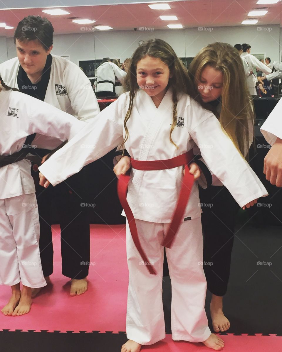 Karate masters tying belt of children