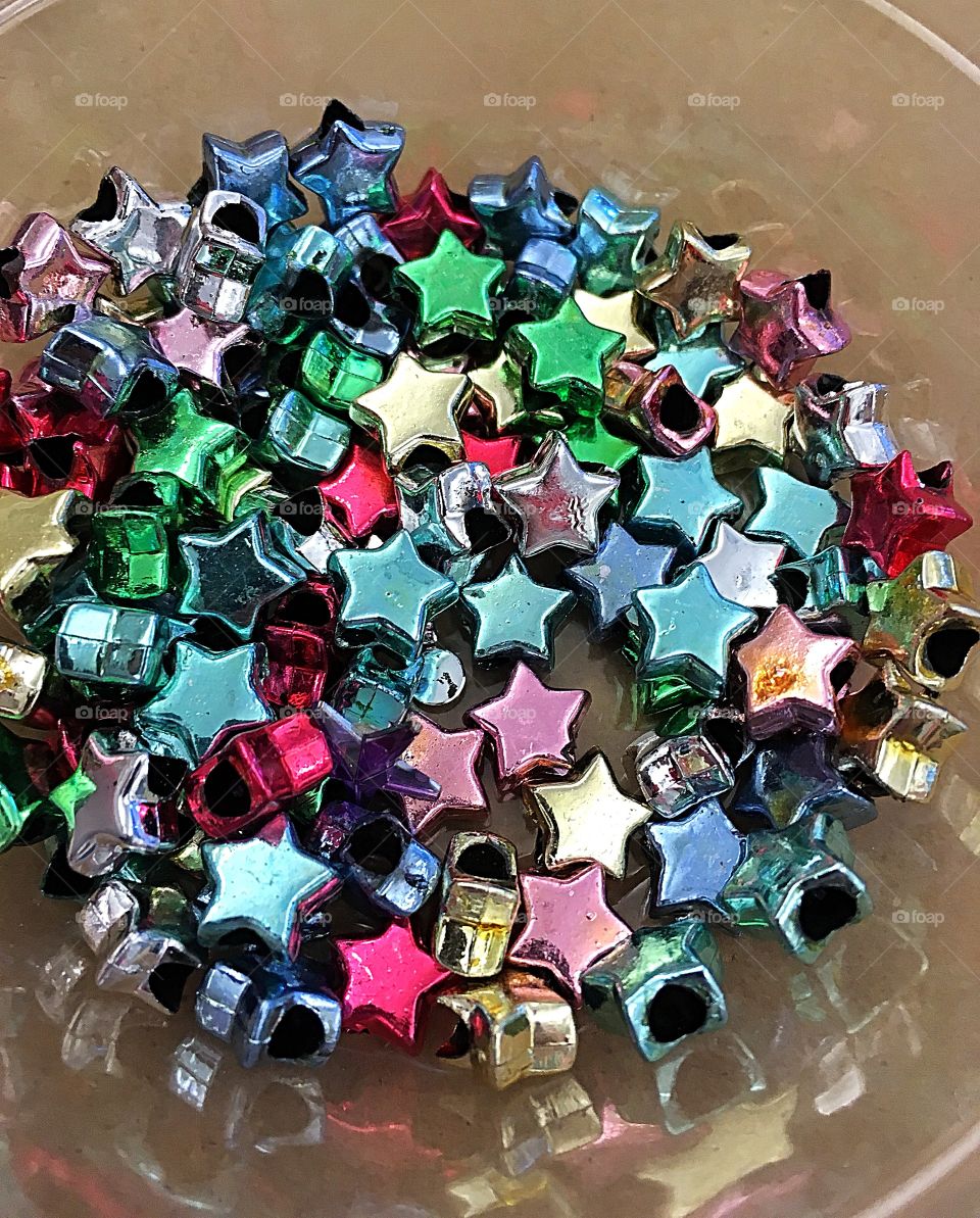 A cup full of stars.  Lots of colorful star beads in a cup at the ready for a craft project. 