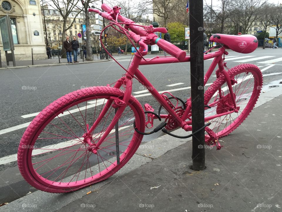 Pink bycicle standing beside the street