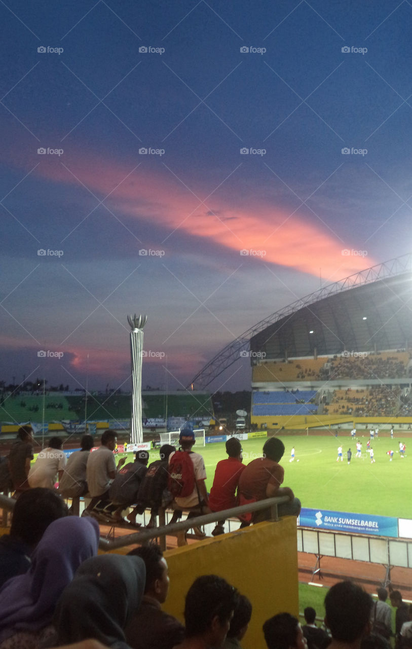The Supporters Enjoy Watching The Match of Sriwijaya Football Club with an Amazing View of Sunset