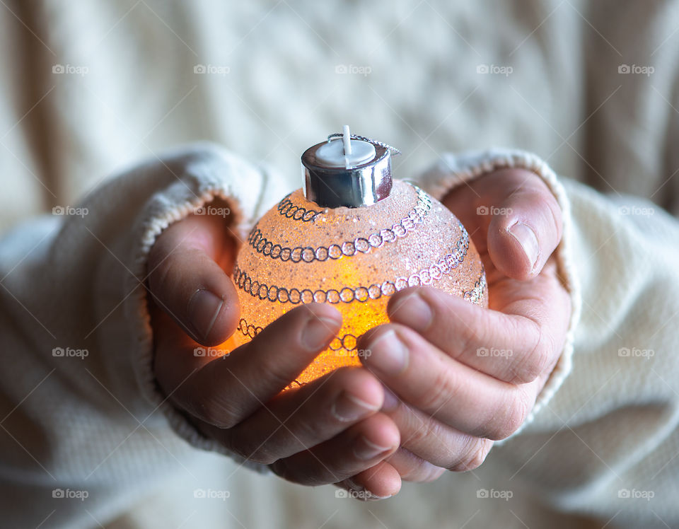 Close up of female hands holding Christmas bauble, light in hands