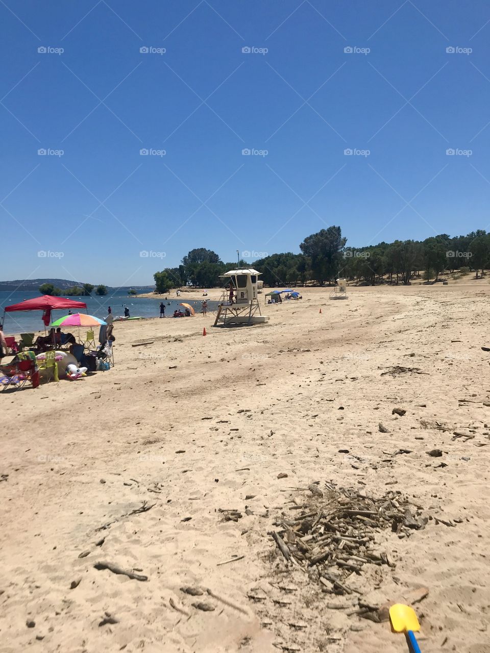 Sandy beaches - pop of color, yellow shovel, blue Skies and red, orange, green, & pink umbrellas 