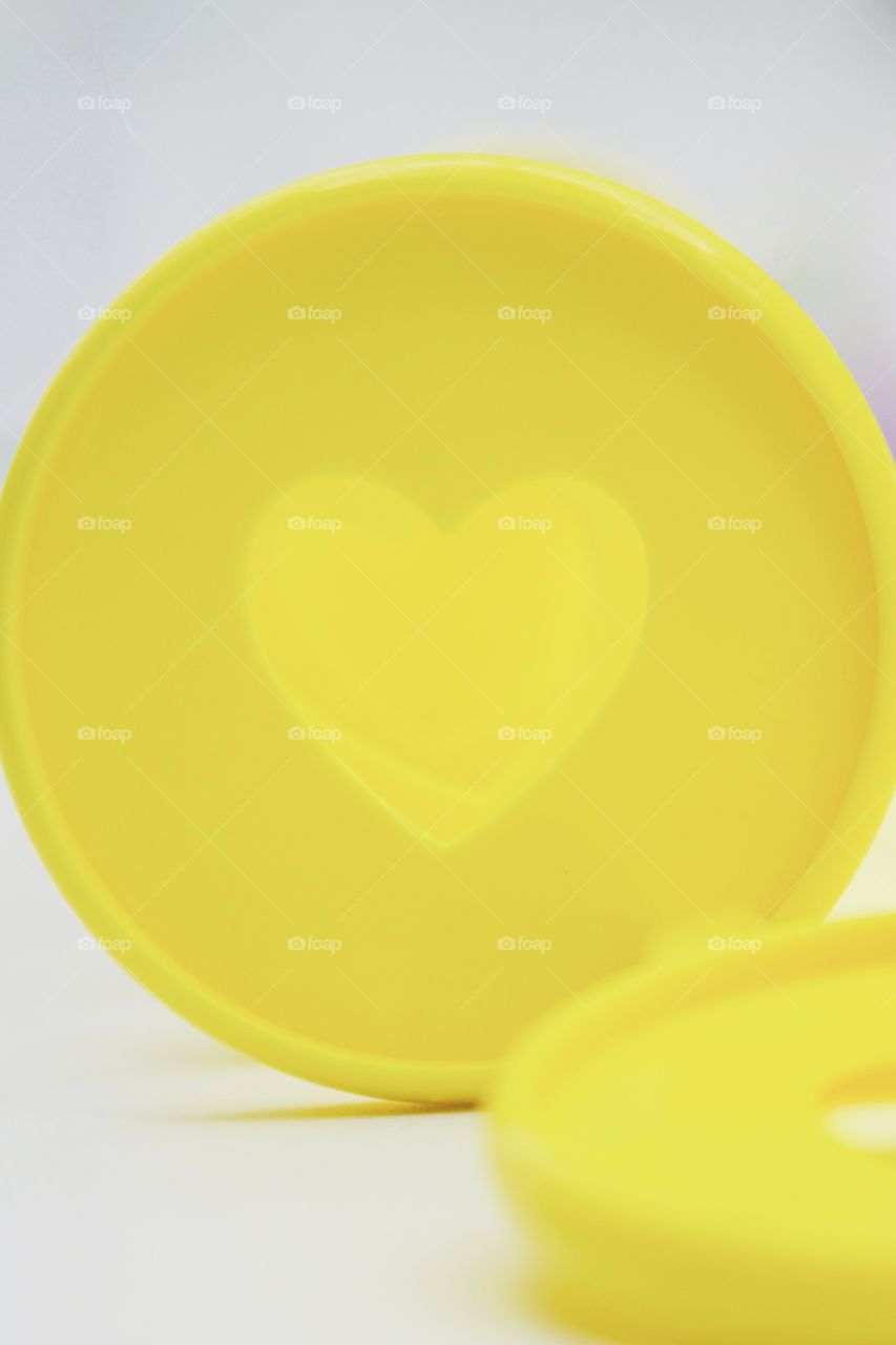 Closeup of yellow discbound disc with heart-shaped cut-out  for discbound planner against white background