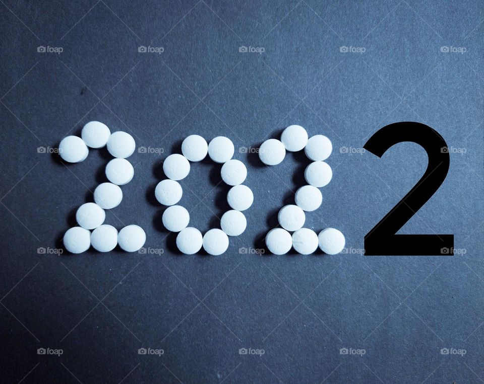 new year 2022 with white colour and last number 2 it's with black colour to distinguish ,  pills concept , blue background