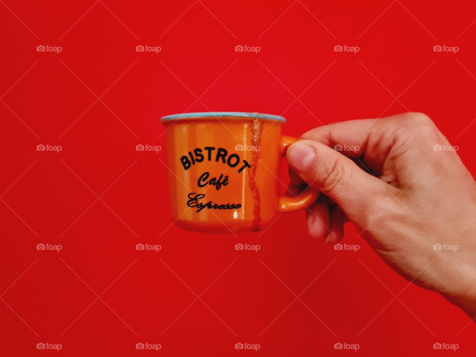 hand holds cup of coffee on red background